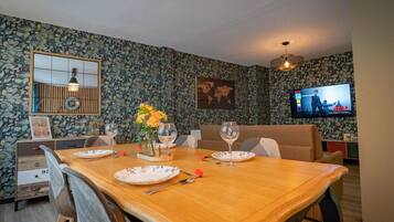Un comedor con una mesa de madera, sillas y un televisor montado en la pared.
