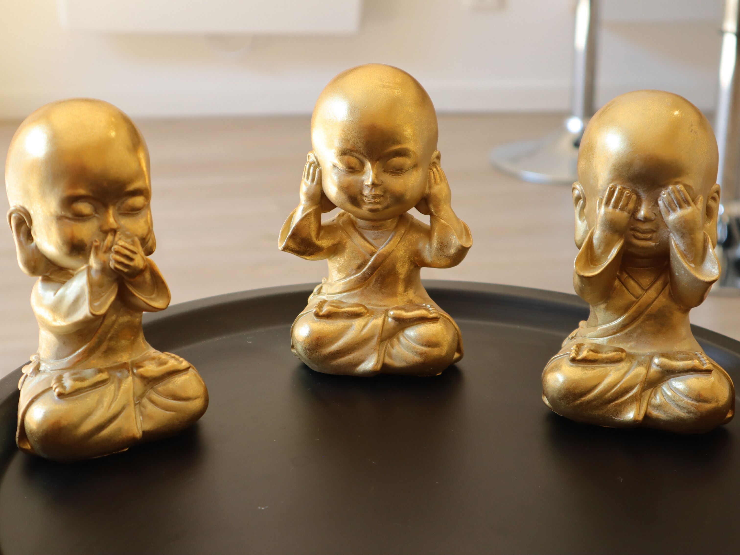 Three golden Buddha statues on a black surface.