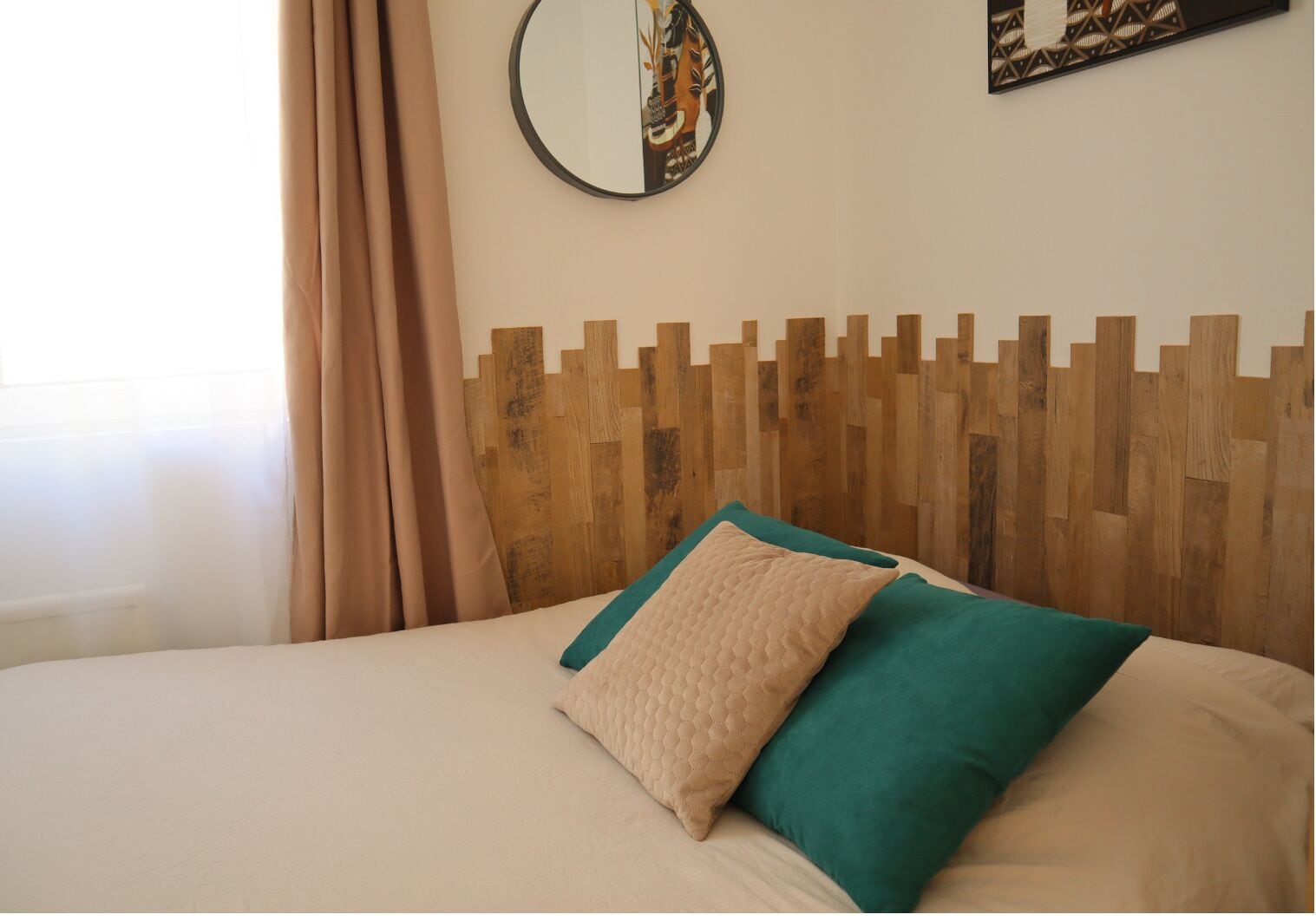 Una cama con cabecera de madera, ropa de cama color beige y dos almohadas.