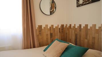 Una cama con cabecera de madera, ropa de cama color beige y dos almohadas.