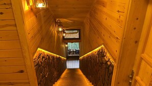 A wooden interior with a staircase leading to a room with a view. - Yamaçda Suit Otel (Camlihemsin)