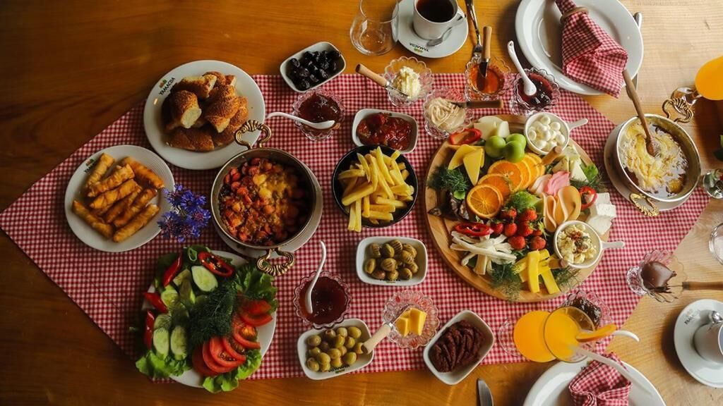 A table set with various dishes including bread, salads, and cheese, arranged on a red and white checkered tablecloth.