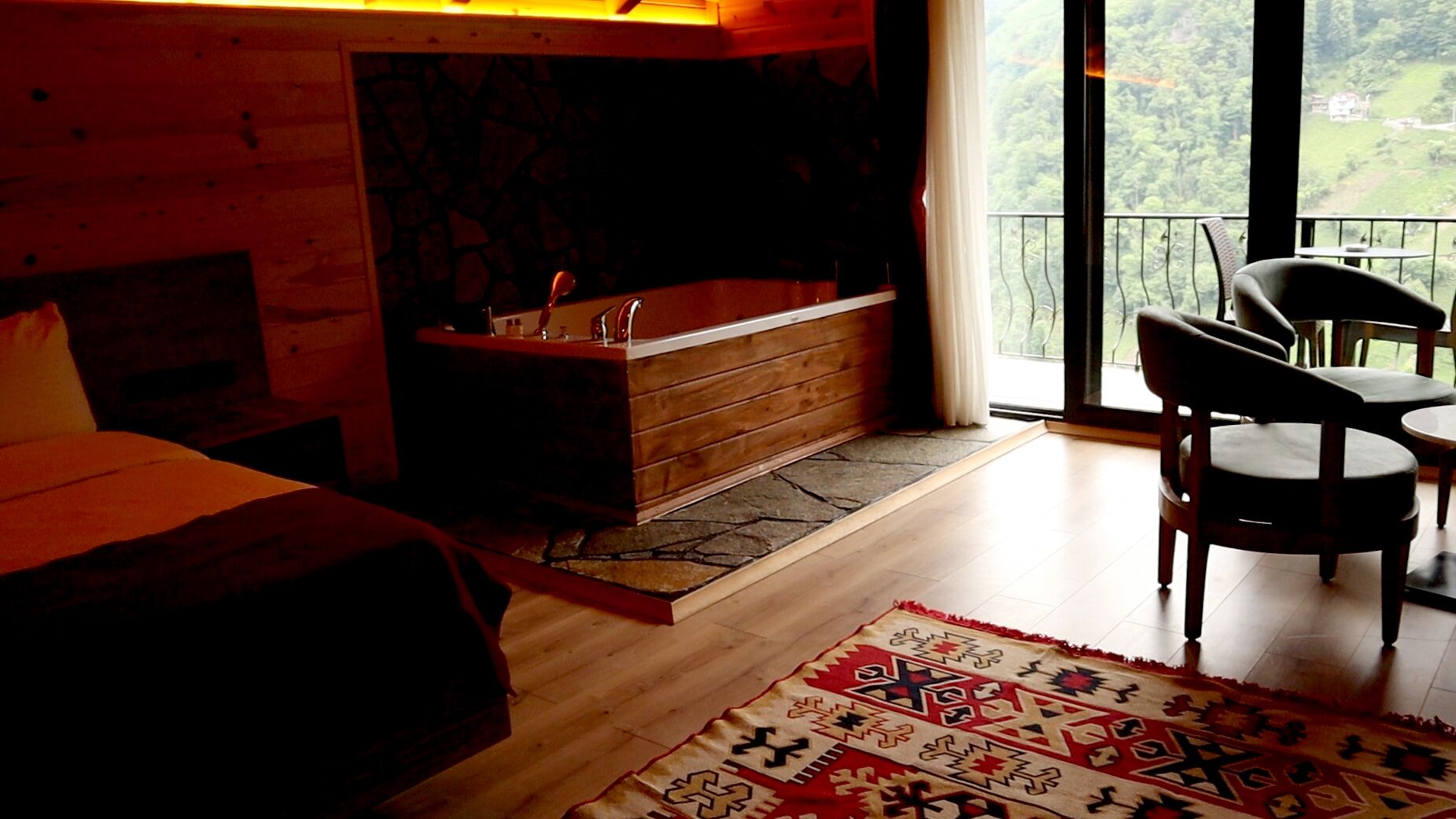 Una habitación acogedora con detalles de madera, un ventanal grande, una bañera y un comedor.