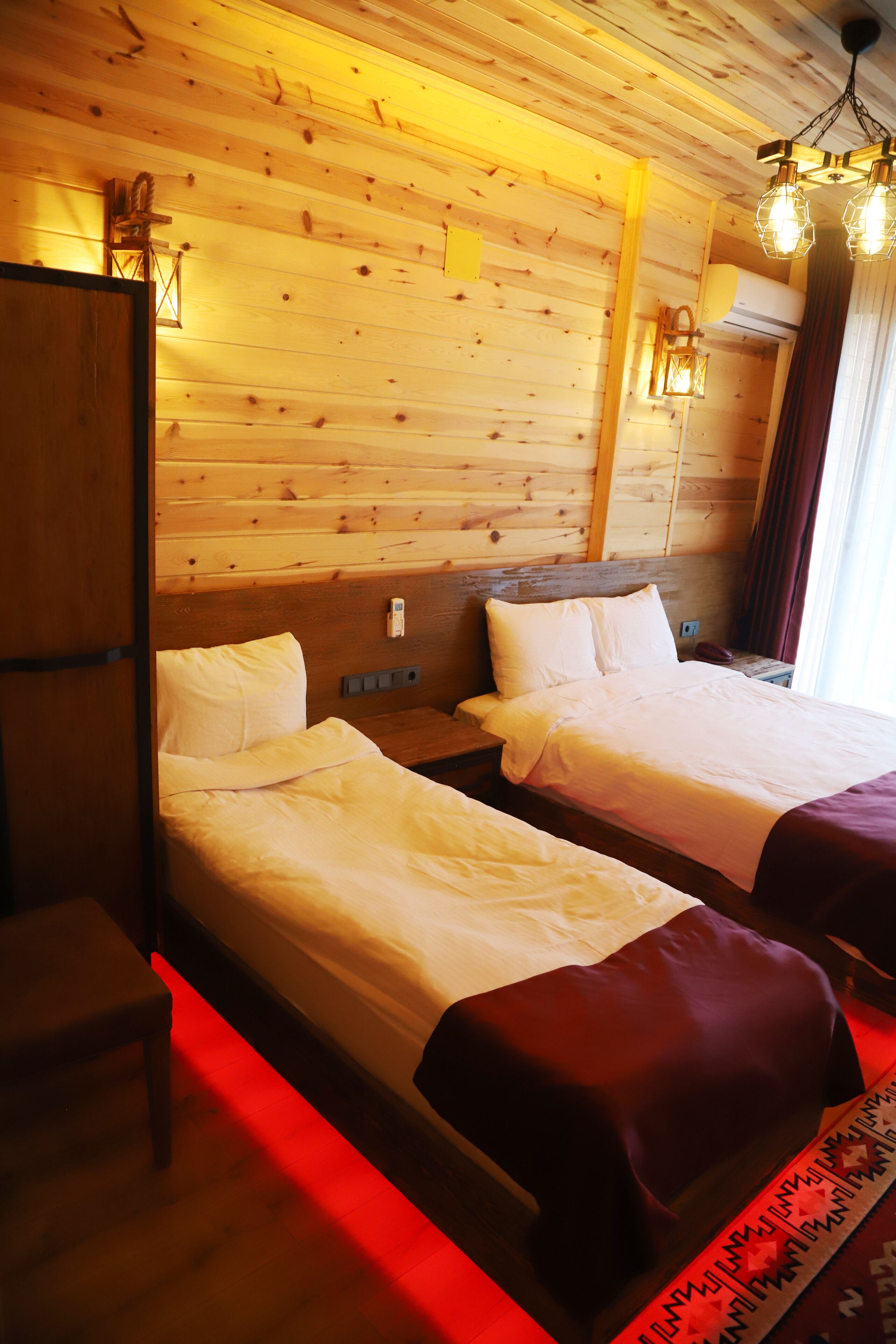 A room with two beds, wooden walls, and a red-lit floor.