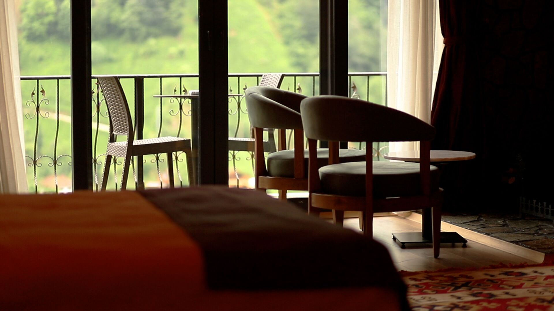 Habitación de hotel con balcón, dos sillas, una mesita y una cama.