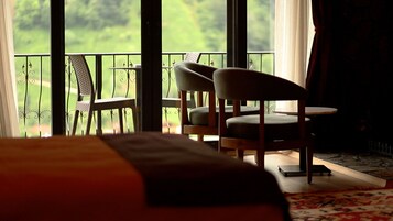 Habitación de hotel con balcón, dos sillas, una mesita y una cama.