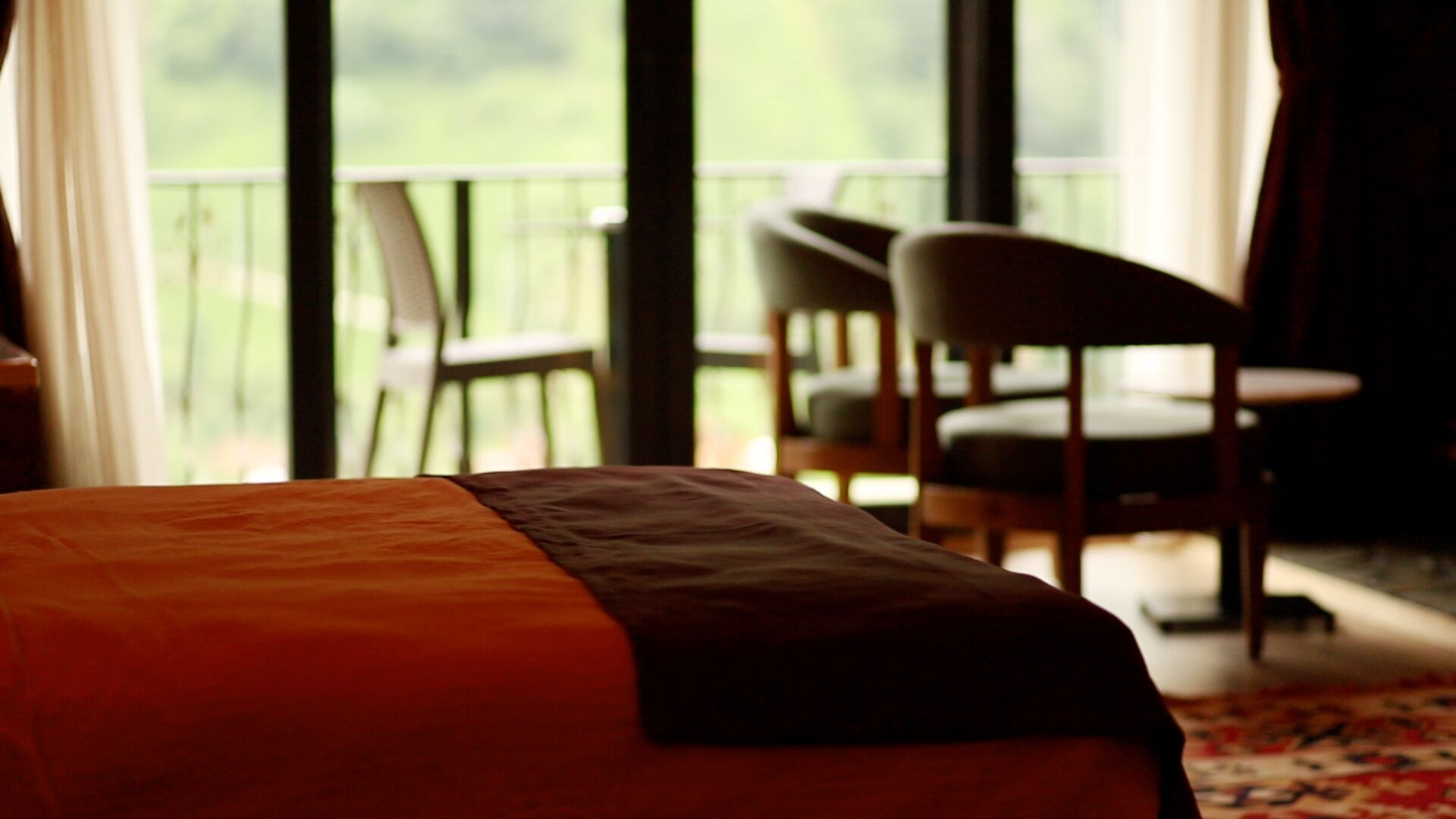Una habitación de hotel con una cama, una silla y vistas a un balcón con sillas.