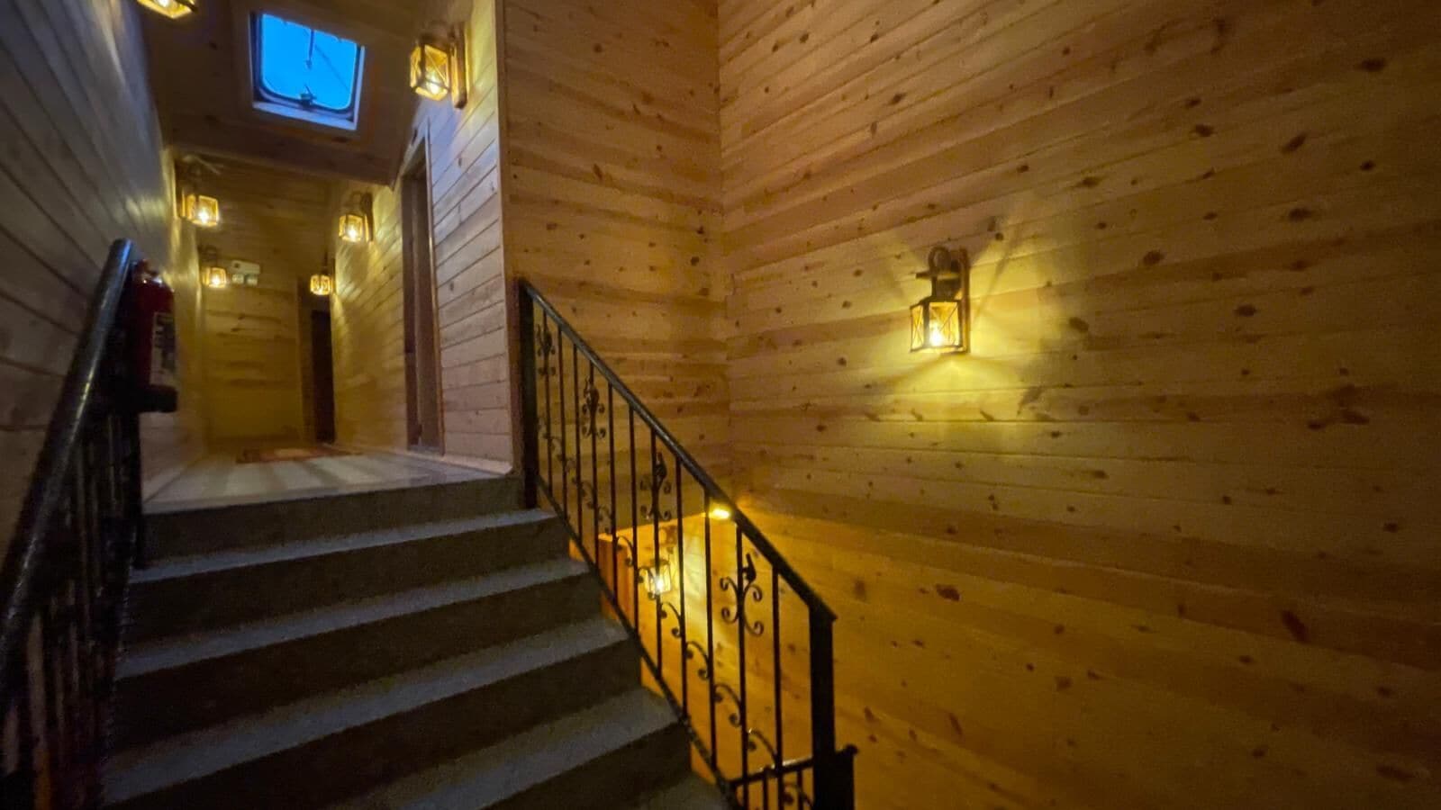 Un interno in legno con una scala, luci a parete e uno schermo televisivo.