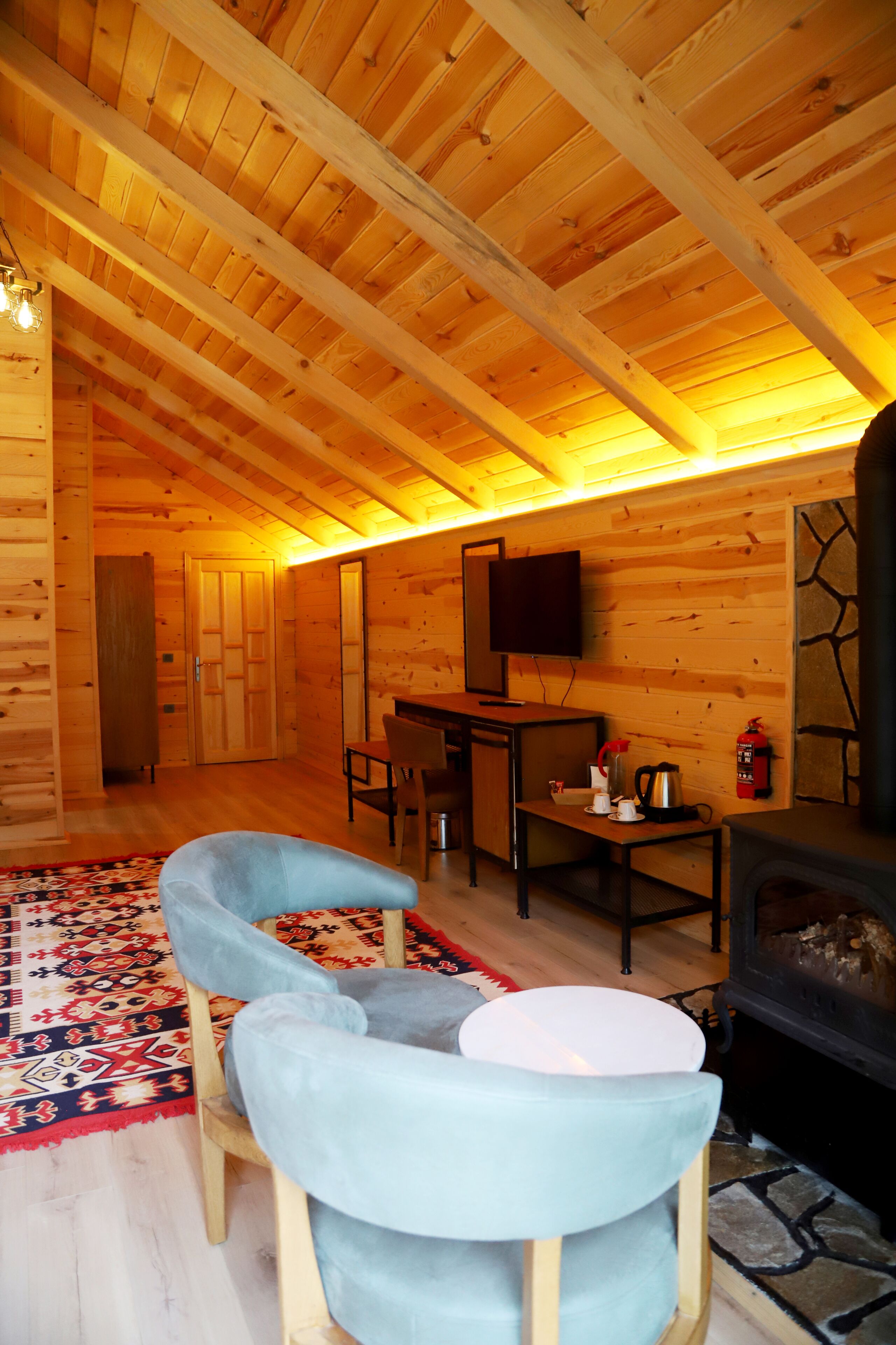 Ein gemütliches Holzhaus-Interieur mit Essbereich, Kamin und Fernseher.