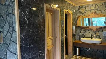 Um banheiro com parede de mármore, porta de madeira, pia com torneira e parede de pedra.