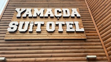Un letrero con el texto 'YAMACDA SUITOTEL' sobre una pared de madera.