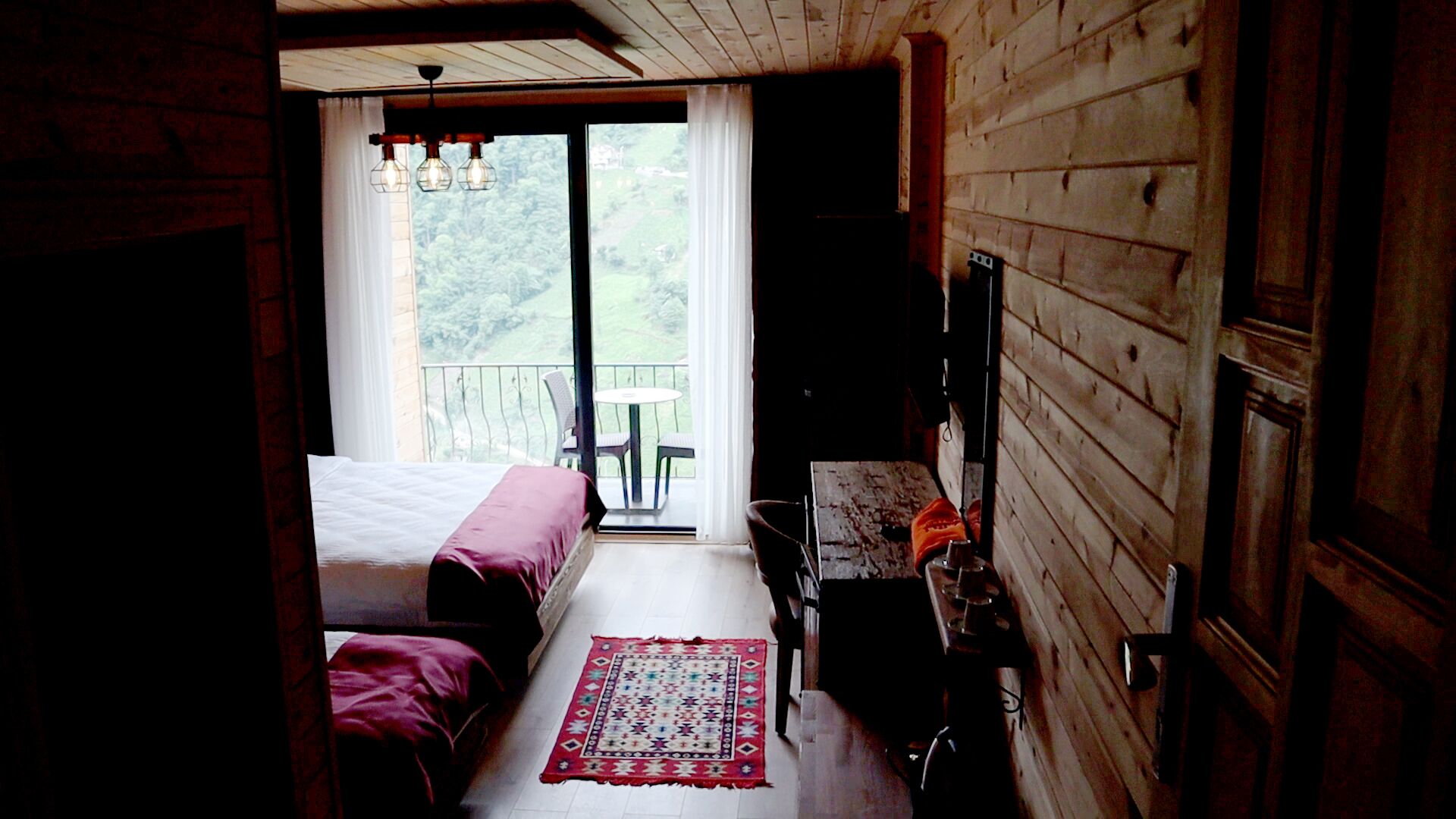 Una habitación con cama, escritorio y ventana con vista a un balcón.