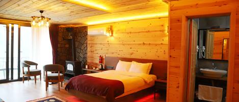 Ein Schlafzimmer einer Holzhütte mit einem Bett, zwei Stühlen, einem Teppich und einer Steinwand.