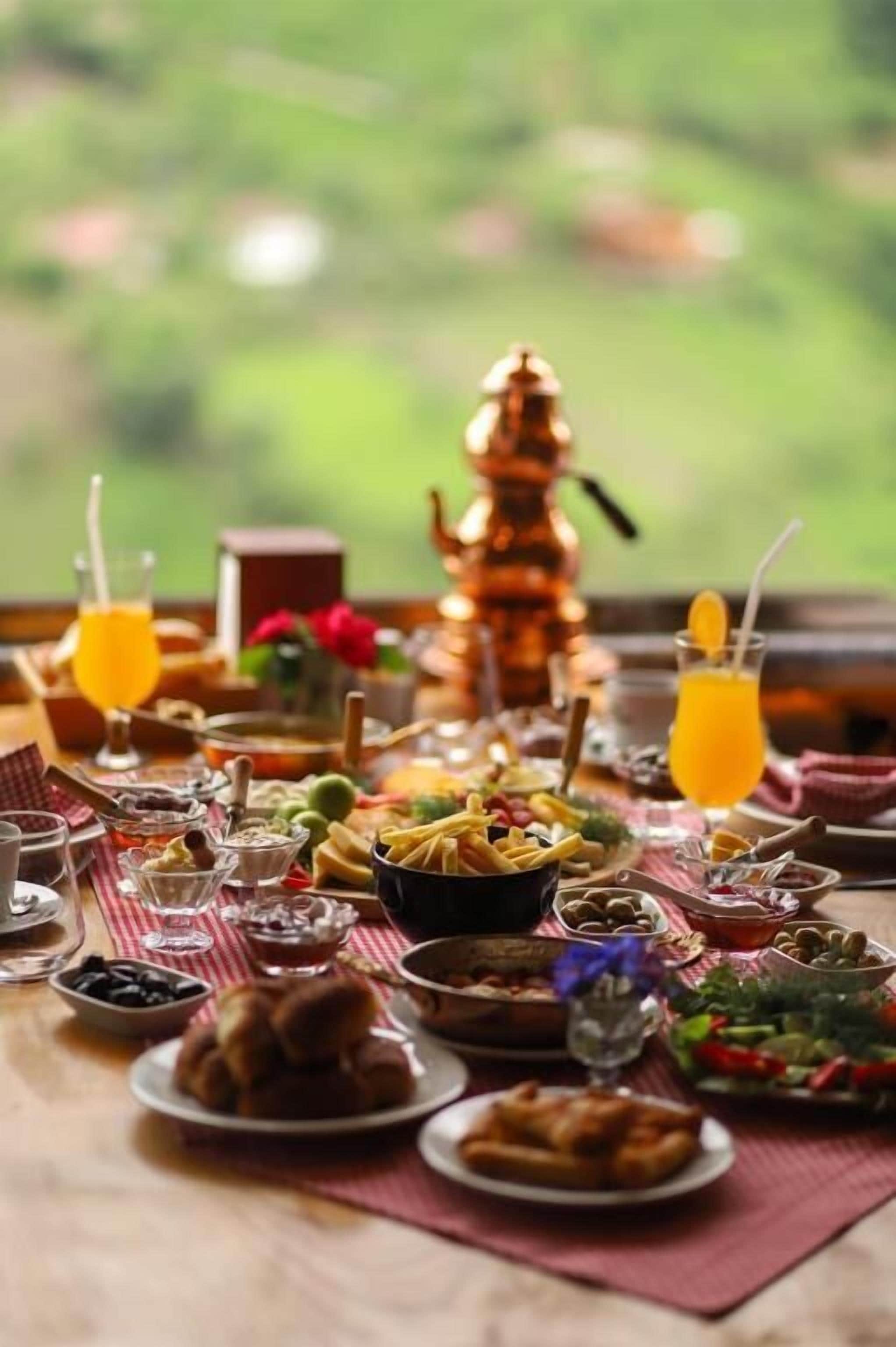 Ein Tisch ist reichhaltig mit Speisen, Getränken und einem Kupfertopf gedeckt, vermutlich für eine Mahlzeit.