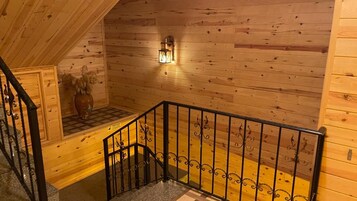 A wooden interior with a staircase, a wall-mounted light fixture, and a decorative vase.