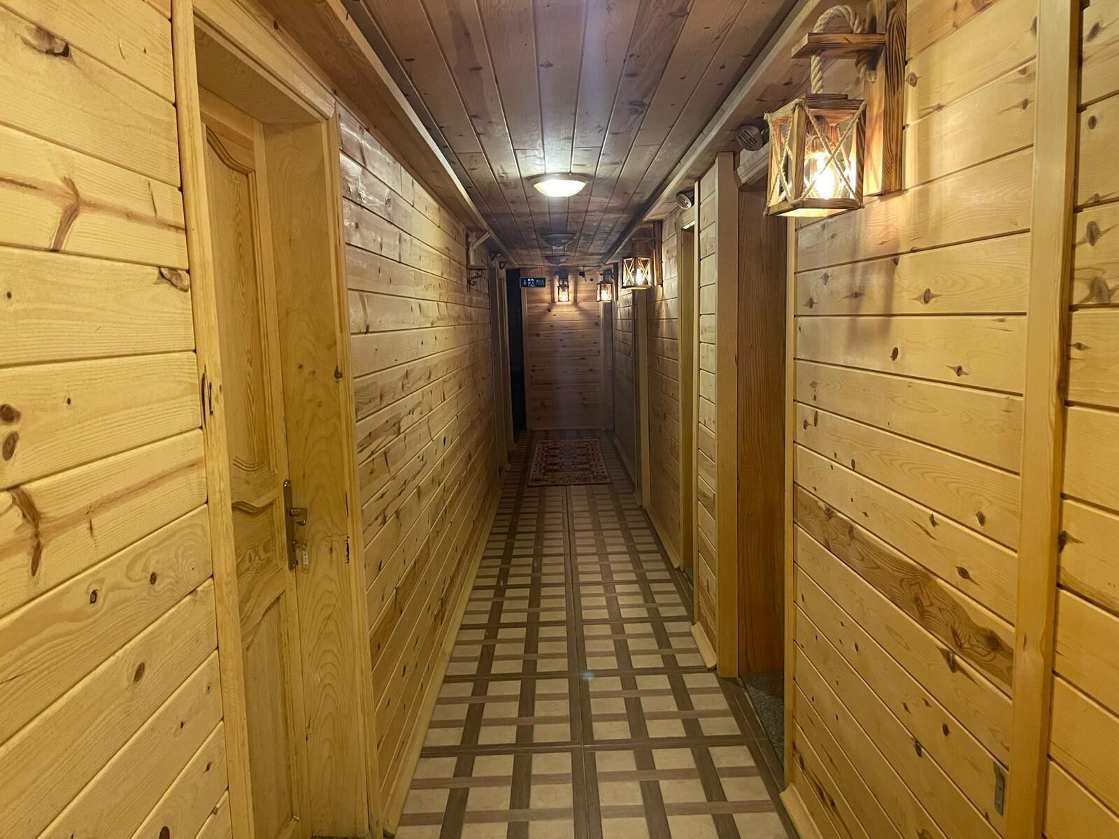 A wooden hallway with a checkered floor and wooden walls.