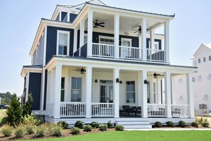 Stunning two-story building with a central entrance and two balconies, each with a seating area.