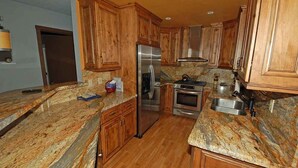 A kitchen with wooden cabinets, granite countertops, stainless steel appliances, and a built-in oven. - 584 Alpine Drive in South Lake Tahoe, CA (South Lake Tahoe)