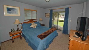 A bedroom with a bed, two nightstands, a television, a window with blinds, and a view of the outdoors. - 584 Alpine Drive in South Lake Tahoe, CA (South Lake Tahoe)
