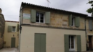 Un bâtiment à deux étages, doté d’une façade beige, de volets verts et d’une enseigne indiquant qu’il s’agit d’un commerce.