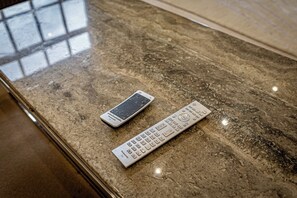 A remote control and a smartphone on a marble surface. -  Serviced Apartments Macclesfield (Macclesfield)