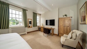 A hotel room with a large bed, a desk with a chair, a television, a wardrobe, and a window with curtains. -  Serviced Apartments Macclesfield (Macclesfield)