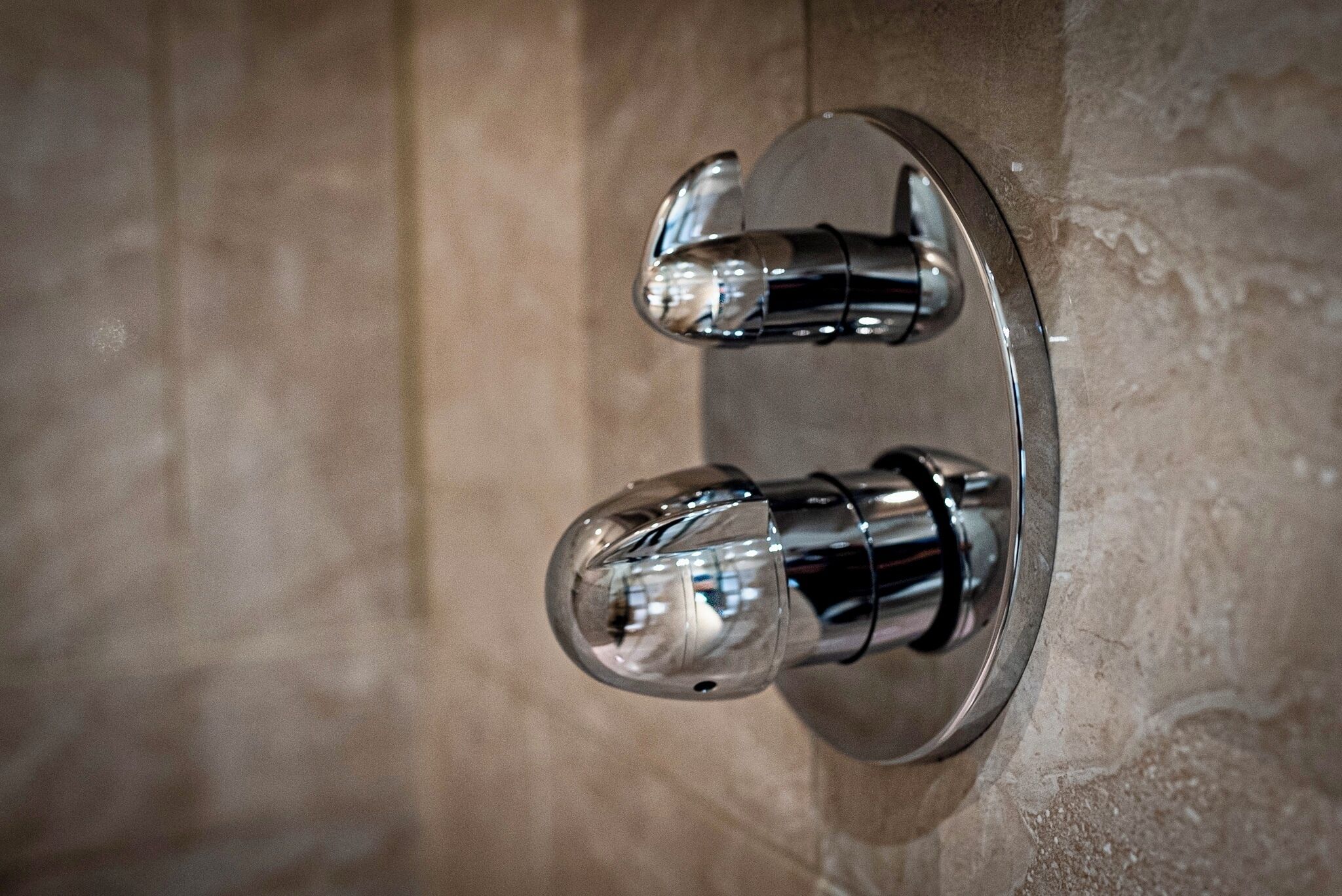 Un baño con un grifo metálico moderno fijado a una pared con superficie texturizada.