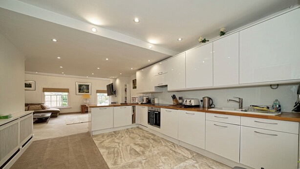 A spacious kitchen with white cabinets, a wooden countertop, and a tiled floor. -  Serviced Apartments Macclesfield (Macclesfield)