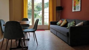 Una sala de estar con sofá, sillas, una mesa y un amplio ventanal con cortinas.