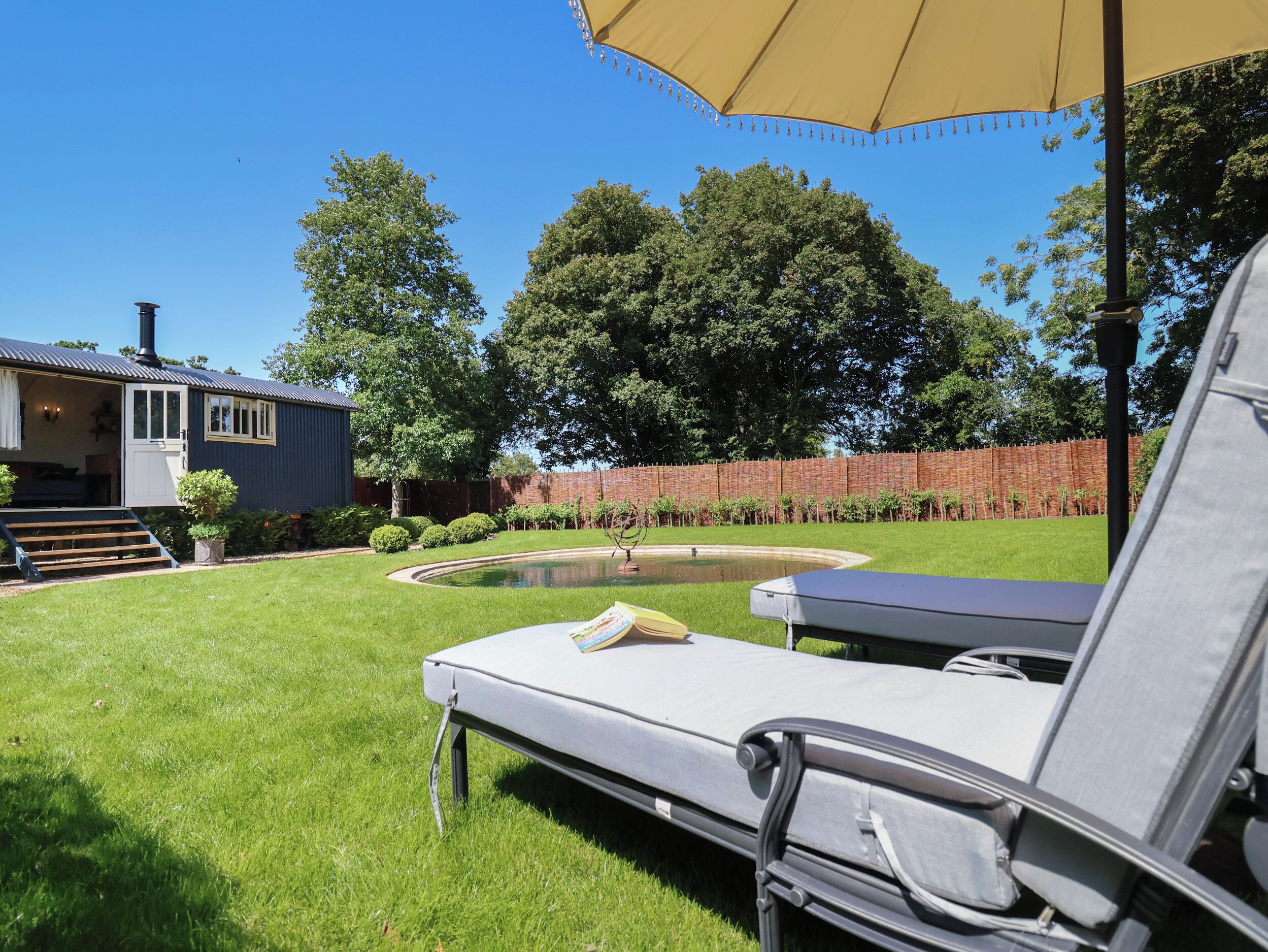 A backyard with a pool, a lounge chair, and a covered patio area.