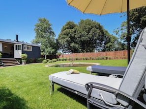 A backyard with a pool, a lounge chair, and a covered patio area. - Utopia (Harleston)
