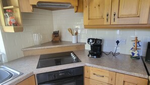 Een keuken met houten kastjes, een fornuis, oven en een koffiezetapparaat.