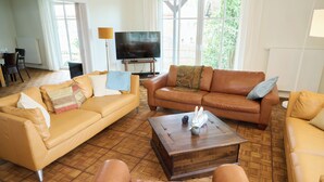 Een woonkamer met twee leren banken, een houten salontafel en een televisie op een standaard.