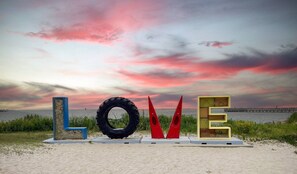 Una playa con la palabra 'LOVE' escrita en letras grandes, cada letra hecha de diferentes materiales como neumáticos y metal.