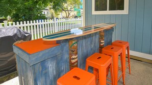 A bar area with a blue and orange bar counter and four orange stools.