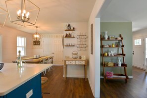 Een keuken met een centraal eiland, houten planken en een eethoek met stoelen en een tafel.