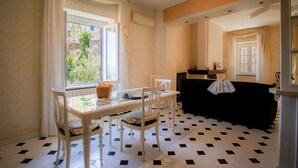 Un comedor con mesa y sillas, un sofá negro y una ventana con cortinas.