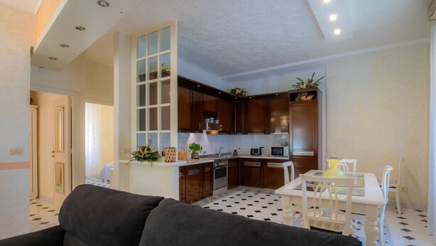 Una cocina moderna con armarios de madera oscura, una encimera blanca y una zona de comedor con una mesa y sillas blancas.