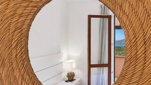 Un dormitorio con cama, mesita de noche, lámpara y vistas a un balcón con puerta.