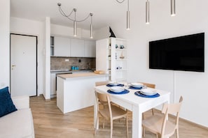 Une cuisine moderne avec des meubles blancs, un îlot central et des luminaires suspendus.