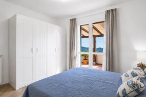 Een slaapkamer met een bed, een kledingkast en uitzicht door een glazen deur.