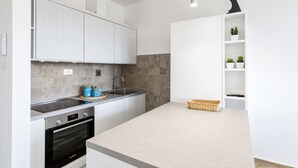 Una cocina moderna con armarios blancos, horno integrado, un fregadero y una encimera.