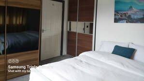Ein Schlafzimmer mit einem Bett, einem Kleiderschrank und einem Bild an der Wand.
