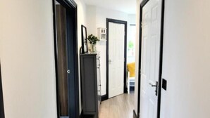 Ein Flur mit einer dunklen Tür, einer weißen Tür und einem Schrank mit einer Pflanze darauf.