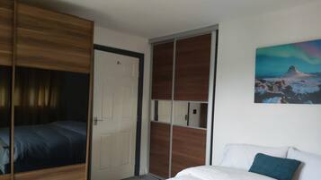A bedroom with a bed, a wardrobe, and a painting on the wall.