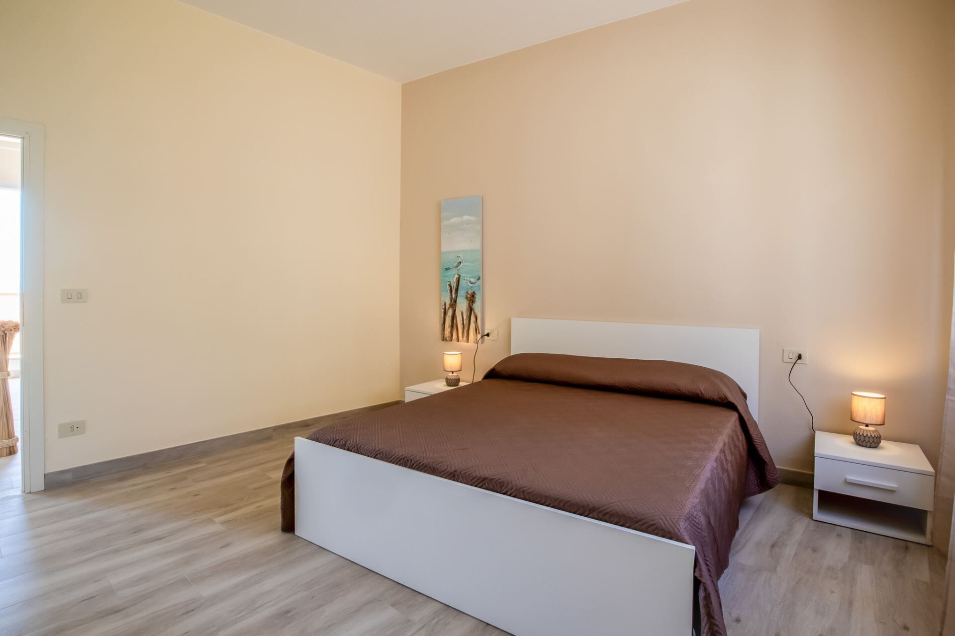 Ein Schlafzimmer mit einem Bett, Nachttischen und einem Wandbild.