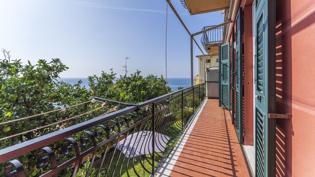 Un balcone con vista sul mare, un pavimento piastrellato e una ringhiera.
