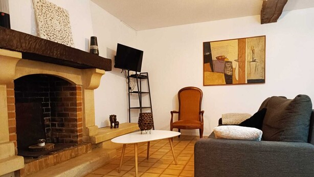 Ein Wohnzimmer mit Kamin, einem grauen Sofa, einem kleinen Tisch und einem Gemälde an der Wand.