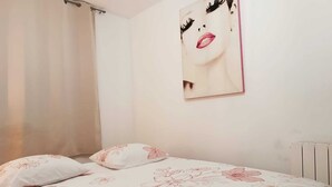 Ein Schlafzimmer mit einem Bett, floralem Bettzeug, einem Wandbild und einer Heizung.