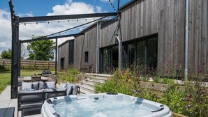 An outdoor patio area with a hot tub, wooden deck, outdoor seating, and a pergola. - The Grain Store, Reepham, Norfolk (Reepham)
